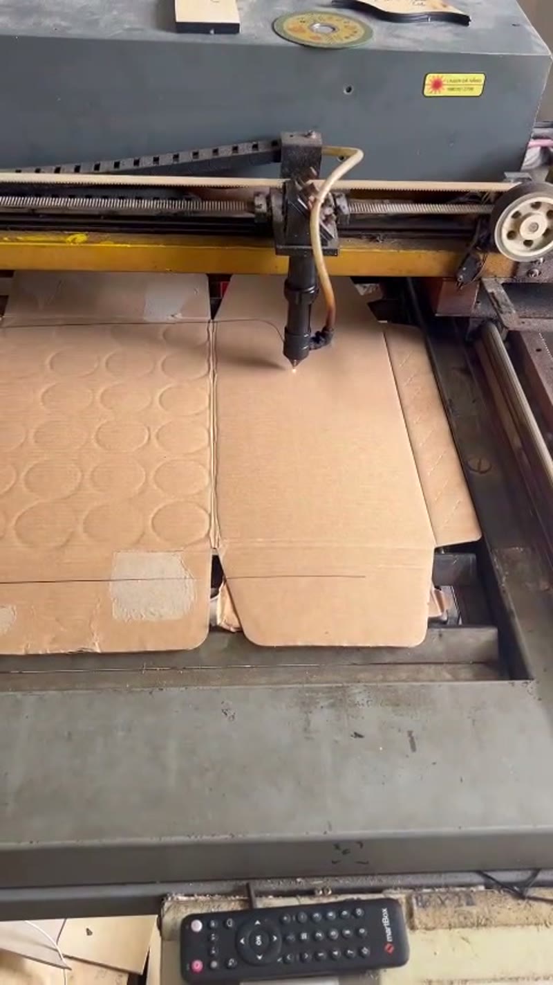 CNC machine precision-cutting a window pattern from card